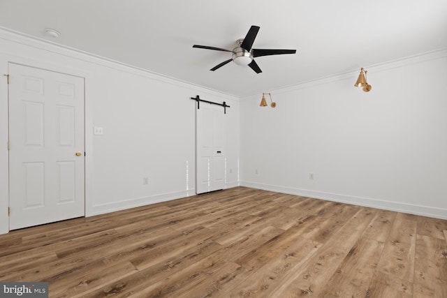 empty room with wood-type flooring, ornamental molding, ceiling fan, and a barn door