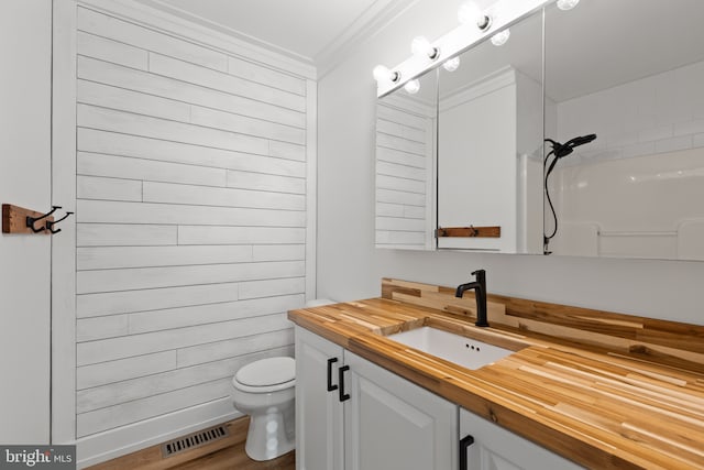 bathroom featuring toilet, wood-type flooring, walk in shower, vanity, and crown molding