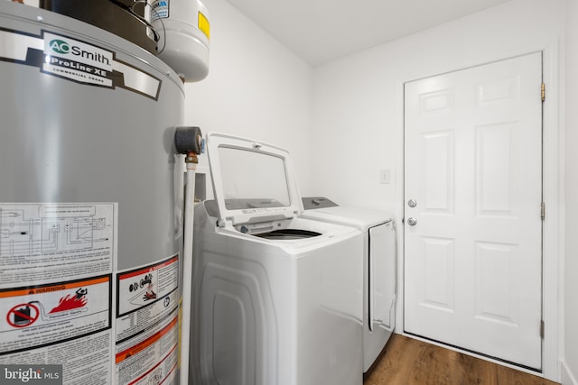 clothes washing area with water heater, washing machine and dryer, and dark hardwood / wood-style floors