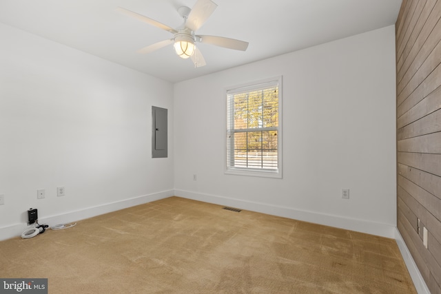 spare room with ceiling fan, electric panel, and light colored carpet