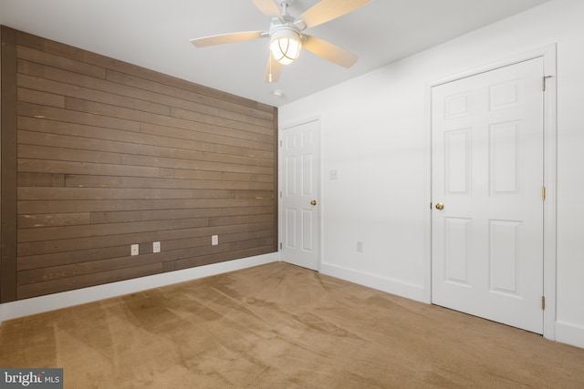 unfurnished bedroom with ceiling fan, wood walls, and carpet flooring