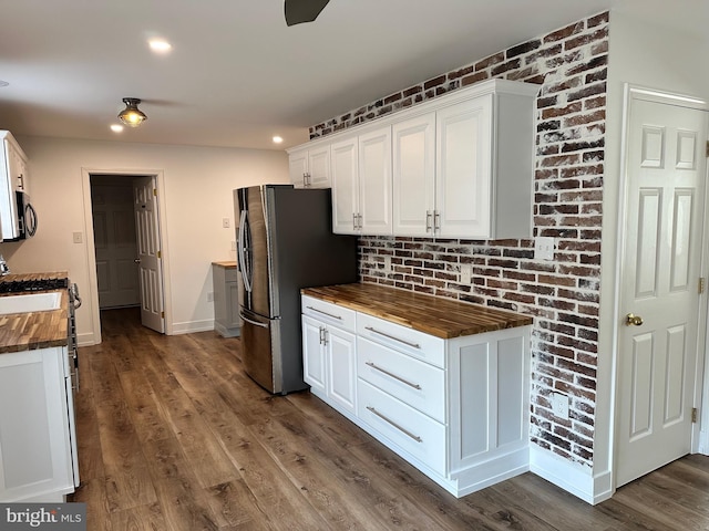 kitchen with butcher block counters, dark hardwood / wood-style flooring, white cabinets, and stainless steel fridge