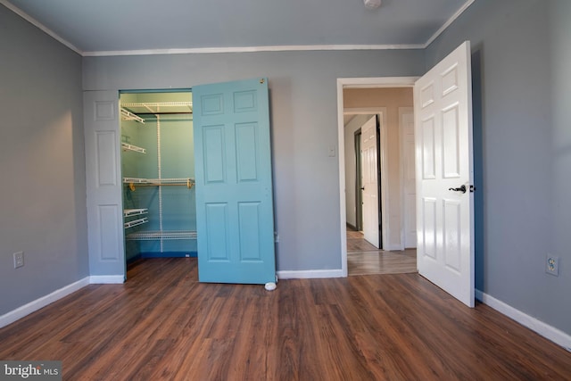 unfurnished bedroom with dark hardwood / wood-style floors, crown molding, and a closet