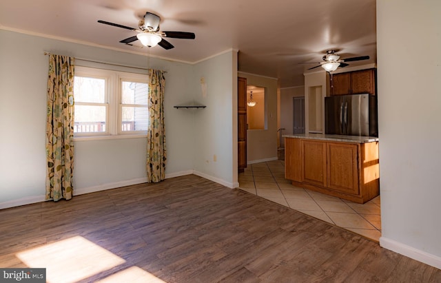 unfurnished living room featuring crown molding, ceiling fan, and light hardwood / wood-style floors