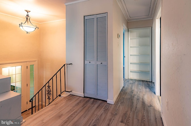 hall with hardwood / wood-style floors, built in features, and crown molding