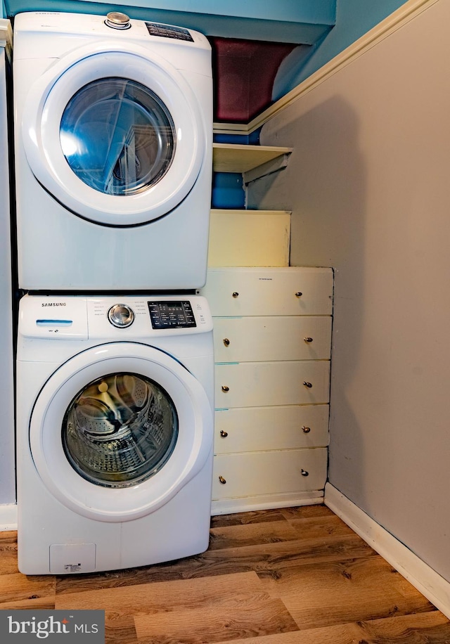 laundry room featuring hardwood / wood-style floors and stacked washer / dryer