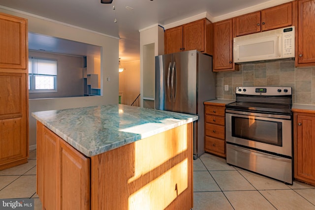 kitchen featuring tasteful backsplash, a kitchen island, light tile patterned flooring, and appliances with stainless steel finishes