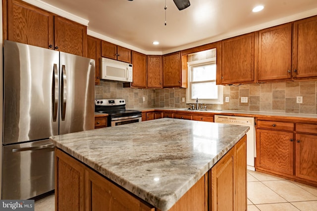 kitchen with ceiling fan, a kitchen island, light stone counters, and stainless steel appliances