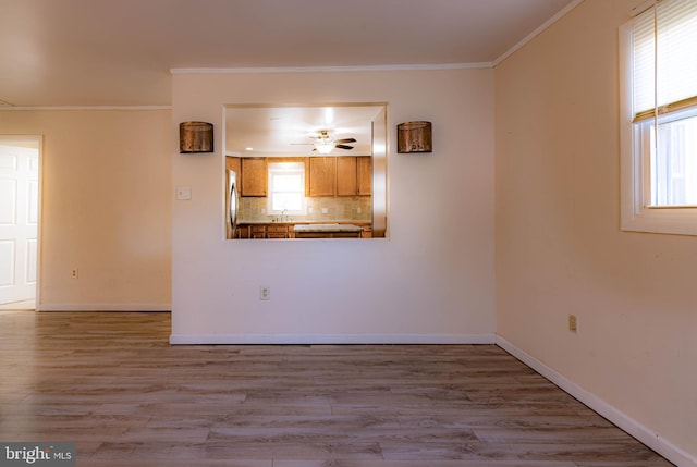 unfurnished room with ceiling fan, sink, light hardwood / wood-style floors, and ornamental molding