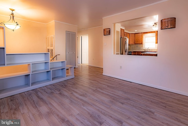 unfurnished living room featuring ceiling fan, light hardwood / wood-style floors, and ornamental molding