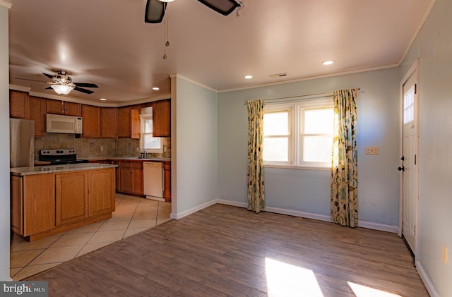 kitchen with backsplash, crown molding, white appliances, and light wood-type flooring