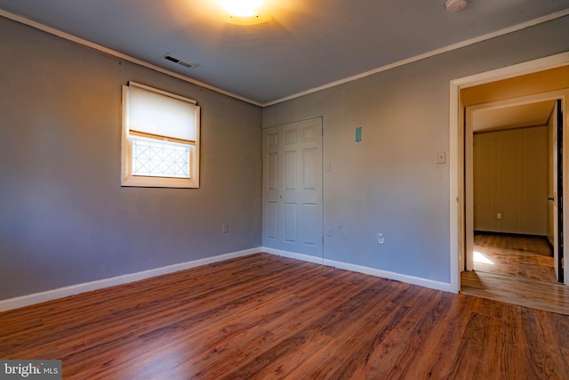 unfurnished bedroom with wood-type flooring and ornamental molding