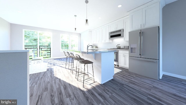 kitchen featuring appliances with stainless steel finishes, tasteful backsplash, decorative light fixtures, white cabinets, and an island with sink