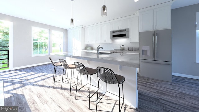 kitchen with a kitchen island with sink, white cabinets, hanging light fixtures, high end white fridge, and tasteful backsplash