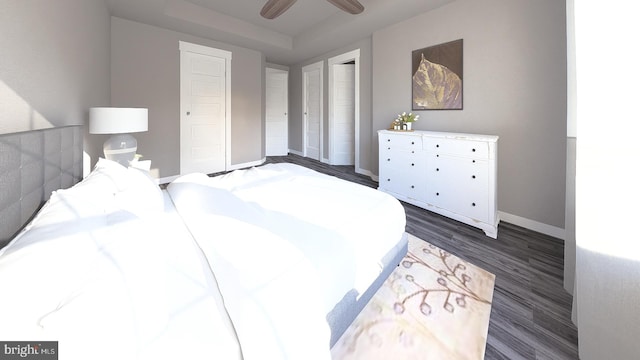 bedroom with a raised ceiling, ceiling fan, and dark wood-type flooring