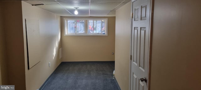 unfurnished room with a paneled ceiling and dark carpet