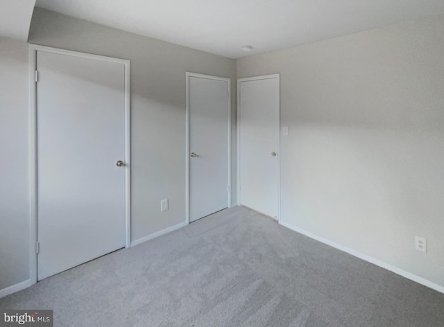 unfurnished bedroom with a closet and light colored carpet