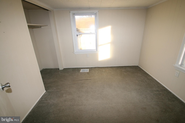 unfurnished bedroom with dark carpet, a closet, and crown molding