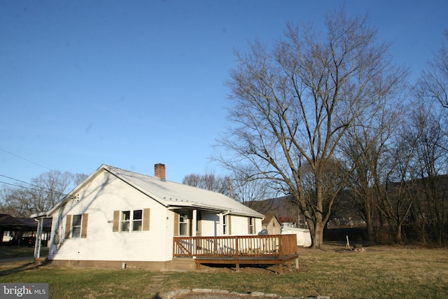 rear view of property featuring a deck and a lawn