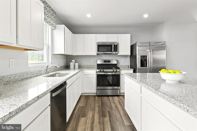 kitchen with light stone countertops, stainless steel appliances, white cabinetry, and sink