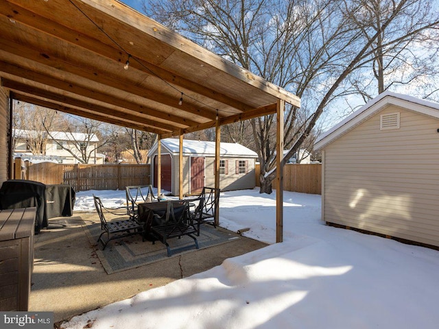 snow covered patio featuring a storage shed