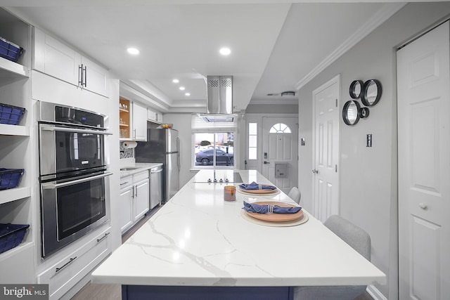 kitchen featuring appliances with stainless steel finishes, white cabinetry, ornamental molding, light stone counters, and a breakfast bar