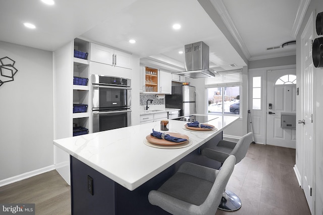 kitchen featuring white cabinets, ornamental molding, stainless steel appliances, and a kitchen island