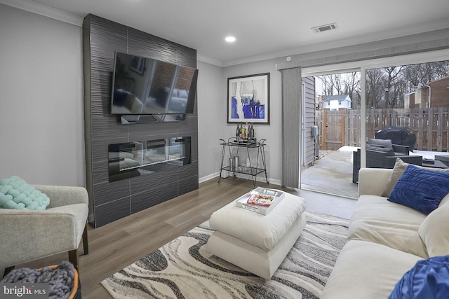 living room featuring crown molding, a fireplace, and wood-type flooring