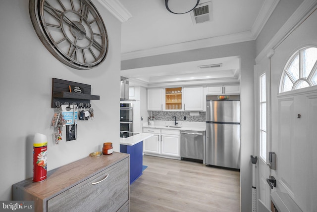 kitchen with decorative backsplash, sink, stainless steel appliances, and white cabinetry