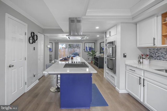 kitchen featuring stainless steel double oven, white cabinets, a center island, a kitchen bar, and island exhaust hood