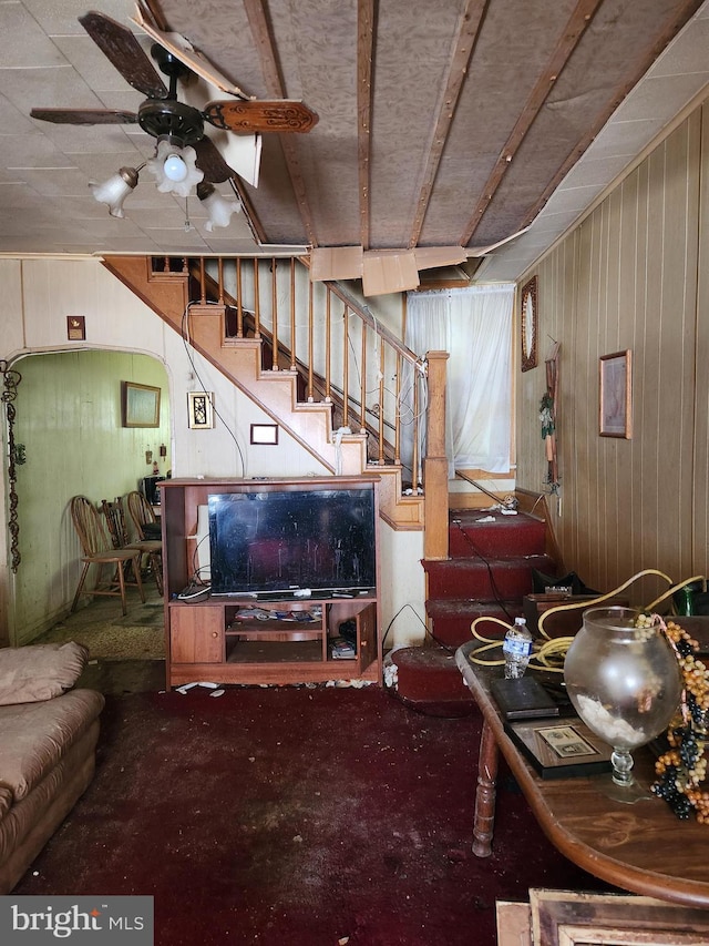 living room featuring ceiling fan and wooden walls