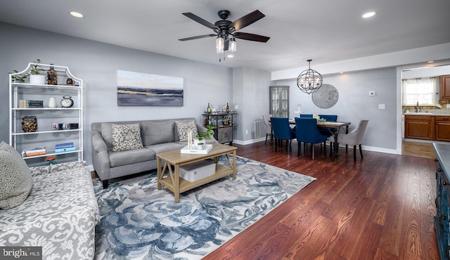 living room with ceiling fan with notable chandelier, dark hardwood / wood-style floors, and sink