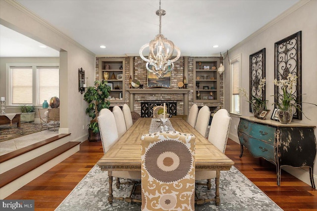 dining room with built in shelves, dark hardwood / wood-style flooring, ornamental molding, and a brick fireplace