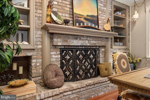 interior details featuring hardwood / wood-style floors, built in shelves, and a brick fireplace