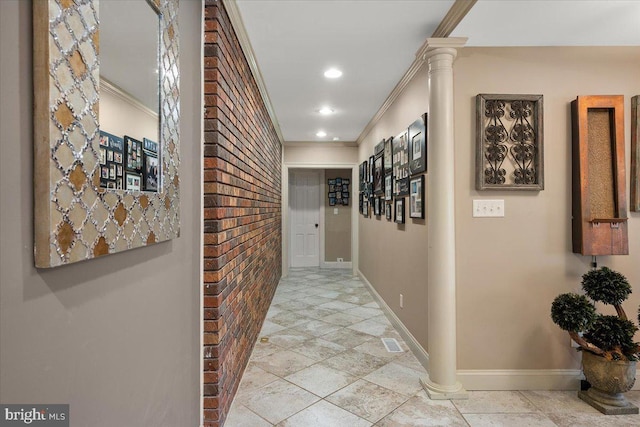 hallway with decorative columns, ornamental molding, and brick wall