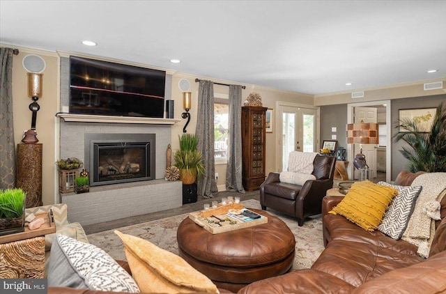 living room featuring a brick fireplace, ornamental molding, and french doors