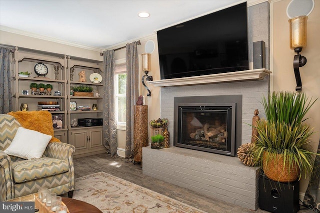 living room with hardwood / wood-style flooring, crown molding, and a fireplace