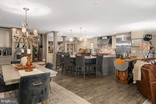 dining space with decorative columns, sink, and dark wood-type flooring