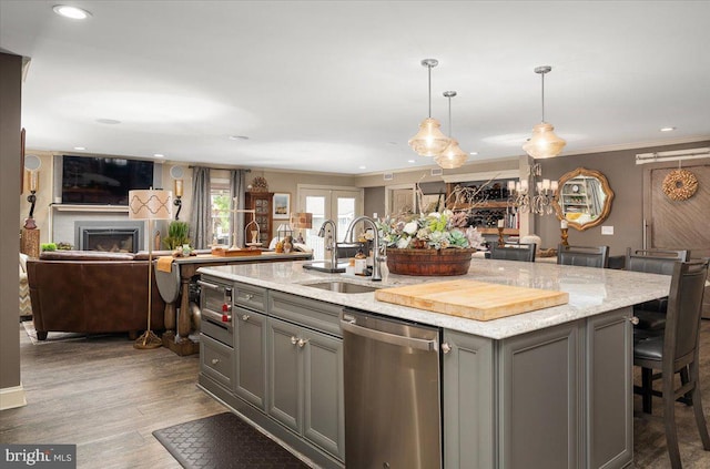 kitchen with a kitchen bar, appliances with stainless steel finishes, sink, gray cabinets, and an island with sink