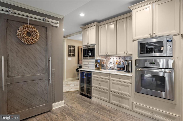 kitchen with beverage cooler, stainless steel appliances, crown molding, hardwood / wood-style floors, and cream cabinets