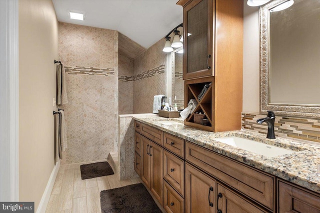 bathroom with hardwood / wood-style floors, vanity, a shower, and backsplash