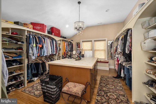 walk in closet featuring hardwood / wood-style floors, a chandelier, and vaulted ceiling