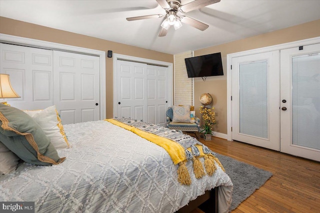 bedroom with french doors, two closets, ceiling fan, and wood-type flooring