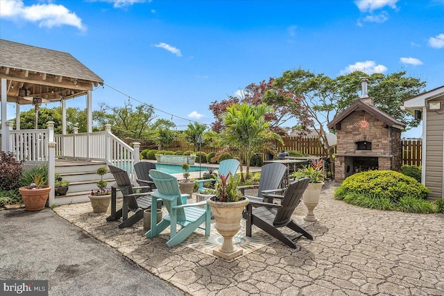 view of patio / terrace featuring an outdoor stone fireplace and a swimming pool side deck