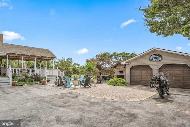 exterior space with a porch, a garage, an outdoor fire pit, and a patio