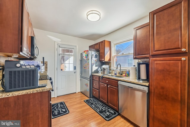 kitchen with sink, stainless steel appliances, light wood-type flooring, and a wealth of natural light