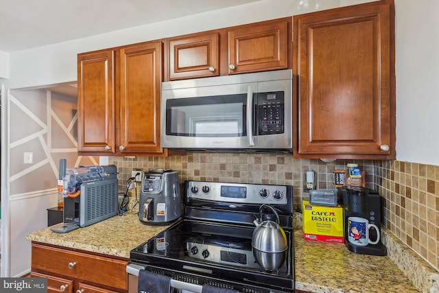 kitchen featuring appliances with stainless steel finishes, light stone countertops, and decorative backsplash