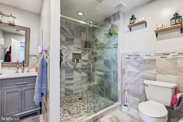 bathroom featuring toilet, an enclosed shower, and tile walls