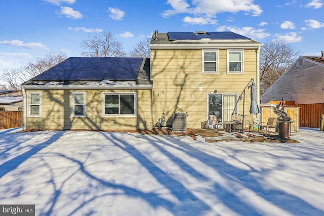 snow covered back of property with solar panels and central AC