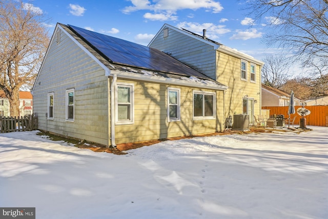 snow covered house featuring central AC unit and solar panels